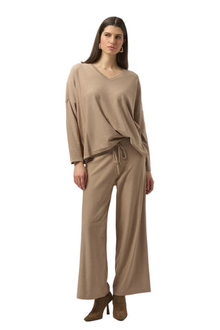 Woman wearing a beige outfit with wide-leg pants on a white background