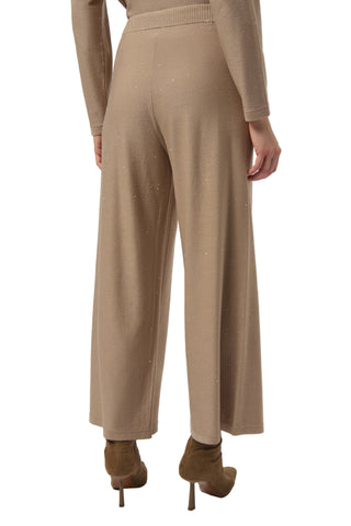 Beige sweater and pants worn by a person on a white background
