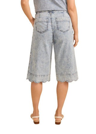 Person wearing light blue denim shorts on a beige background