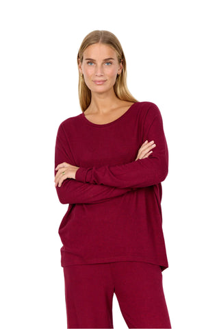 Woman wearing a burgundy loungewear set on a white background