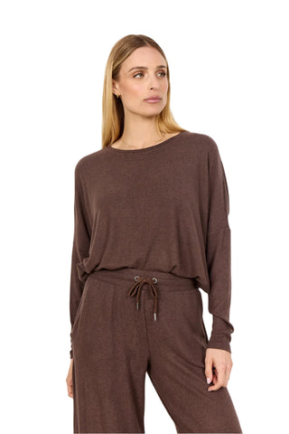 Woman wearing a brown outfit with a long-sleeve top and pants on a white background