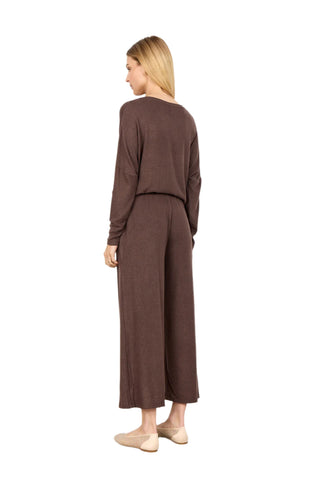 Woman wearing a brown outfit with wide-leg pants against a white background