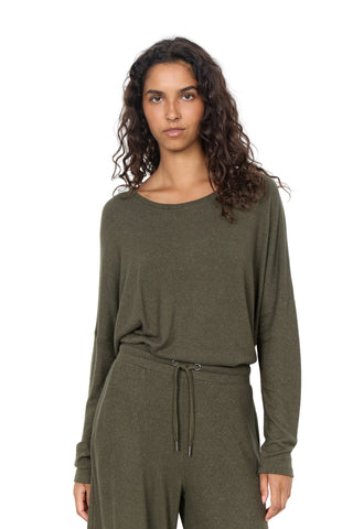 A woman modeling a matching olive green loungewear set consisting of a long-sleeve top and drawstring pants, shot against a plain white studio background.
