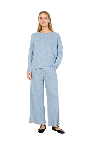 Woman wearing a light blue outfit with wide-leg pants against a white background