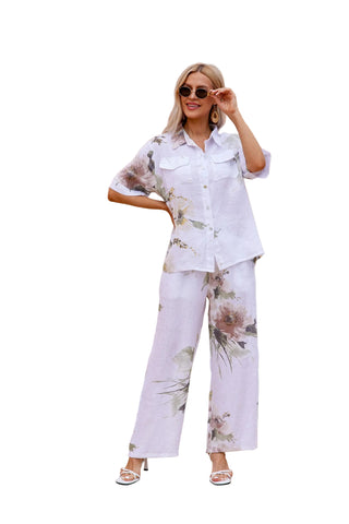 Woman in floral outfit standing in a sunlit outdoor setting with architectural elements.