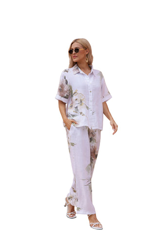 Woman in a floral outfit standing in front of a beige building with columns.