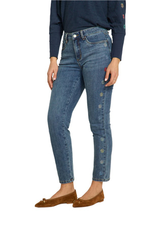 Person wearing blue jeans with decorative buttons on a white background