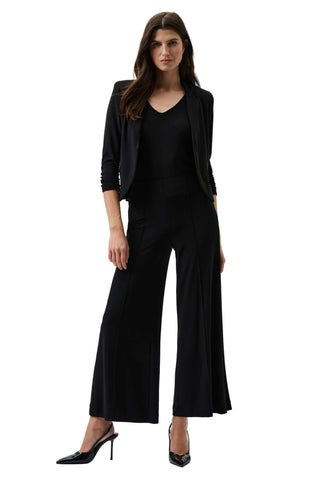 Woman wearing a black outfit with wide-leg pants on a white background