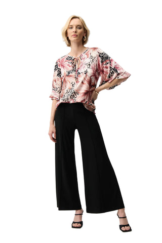 Woman wearing a floral blouse and black pants on a white background