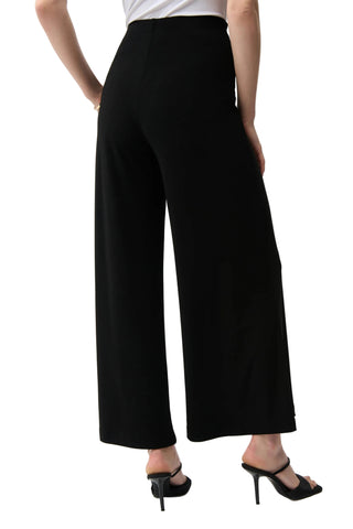 Person wearing black wide-leg pants on a white background