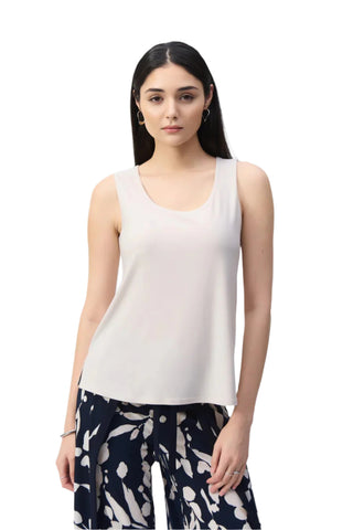 Woman wearing a white sleeveless top and patterned pants on a white background