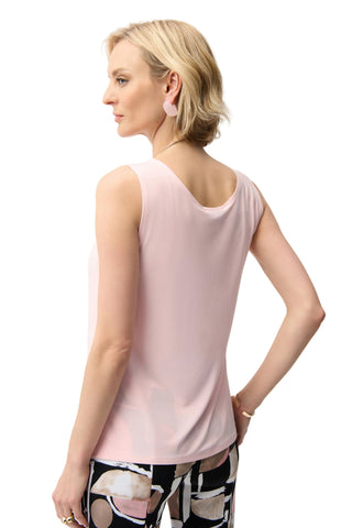 Woman wearing a light pink sleeveless top on a white background