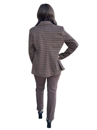 Person in a plaid jacket and pants walking past a store with fall decorations.