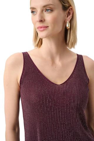 Woman wearing a burgundy sleeveless top with a subtle pattern against a plain background