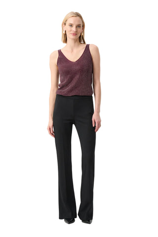 Woman wearing a maroon sleeveless top and black pants on a white background