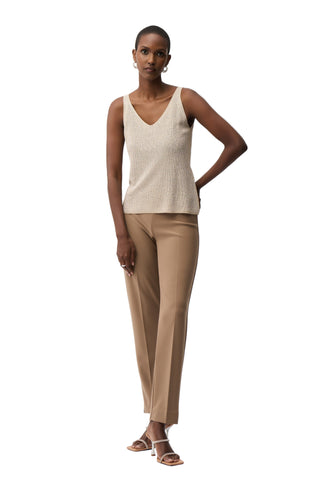 Woman wearing a beige sleeveless top and pants on a white background