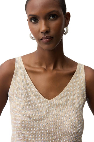 Woman wearing a beige sleeveless top against a plain background