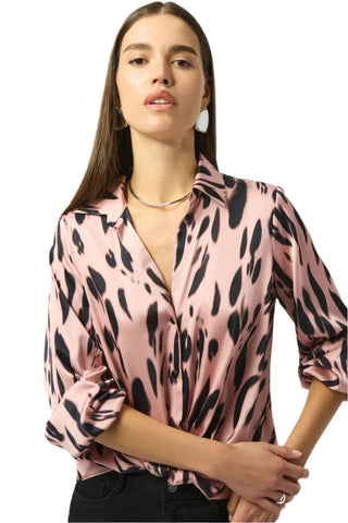 Woman wearing a pink blouse with black animal print pattern on a white background