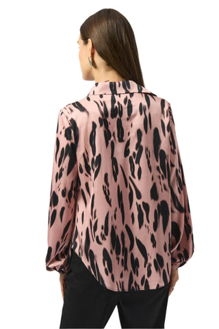 Person wearing a pink blouse with black leopard print pattern on a white background
