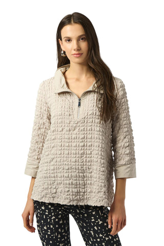 Woman wearing a textured beige pullover with a white background
