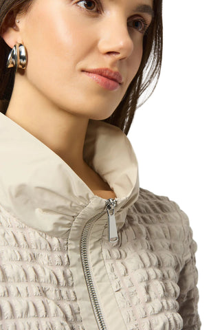 Close-up of a person wearing a beige quilted jacket on a white background