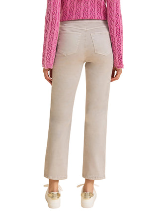 Person wearing light gray pants and a pink knitted sweater on a beige background