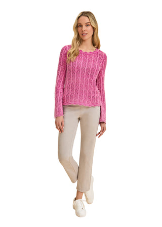 Woman wearing a pink sweater and beige pants on a beige background