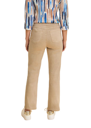 Person wearing beige pants and a patterned shirt on a beige background