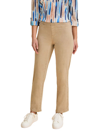 Person wearing beige pants and a patterned shirt on a beige background