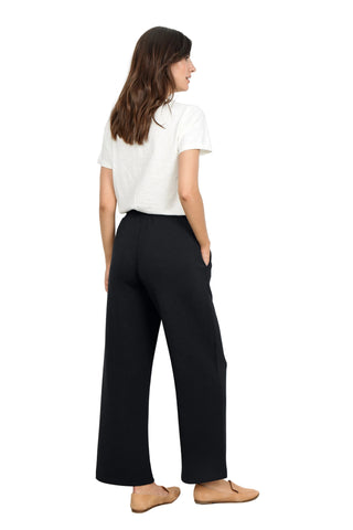 Woman wearing a white t-shirt and black wide-leg pants against a white background