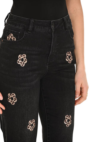 Black jeans with decorative floral patches on a white background