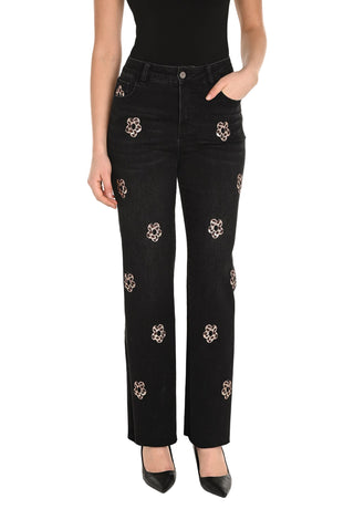 Black jeans with floral embellishments worn by a person on a white background