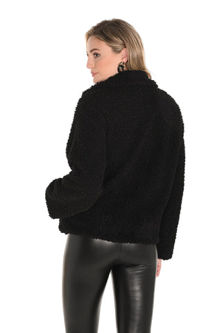 Woman wearing a black fluffy jacket and black pants on a white background