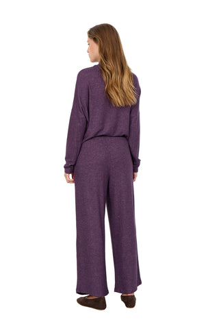 Woman wearing a purple outfit standing against a white background