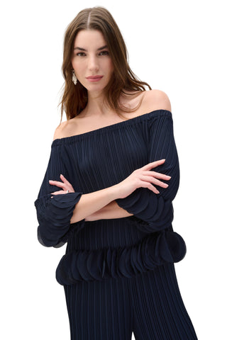 Woman wearing a dark blue off-shoulder top and matching pants on a white background