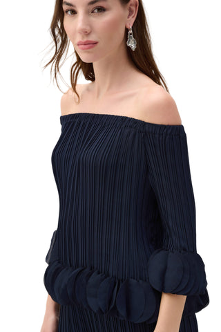 Woman wearing a navy off-shoulder dress with a plain background