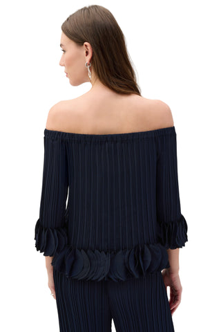 Woman wearing a navy off-shoulder top with ruffled details on a white background