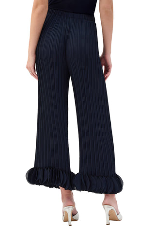Navy pleated pants with ruffled cuffs worn by a person on a white background