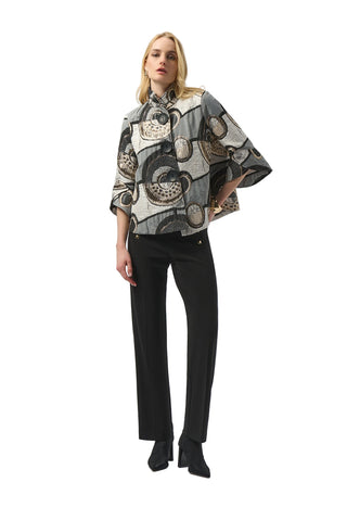 Woman wearing a patterned poncho over a black outfit on a white background