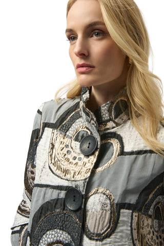Woman wearing a patterned coat with decorative buttons on a plain background