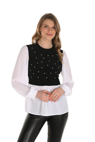 Woman wearing a black top with white polka dots and a sheer white blouse over it on a white background