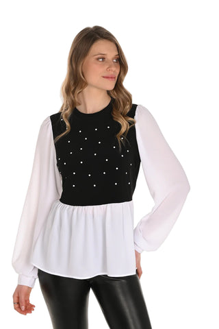 Woman wearing a black top with white polka dots and a white sheer overlay on a white background