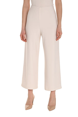 Person wearing a white dress with high-waisted cream pants on a white background