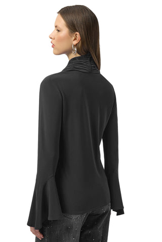 Person wearing a black long-sleeve top with a cowl neck on a white background
