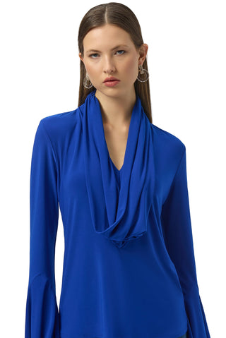 Woman wearing a blue long-sleeve top with a draped neckline on a white background
