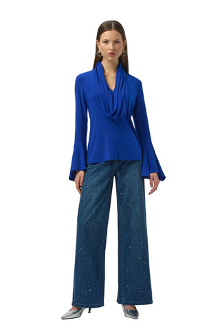 Woman wearing a blue top and wide-leg jeans on a white background
