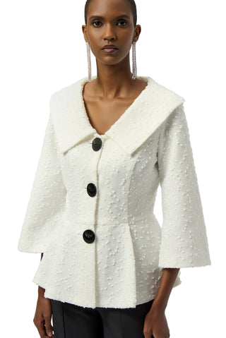Woman wearing a white textured jacket with black buttons on a plain background