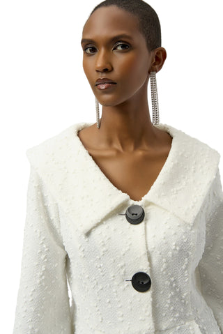 Woman wearing a white textured coat with black buttons on a plain background