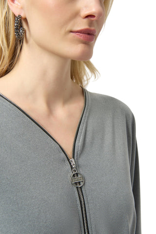 Close-up of a person wearing a gray zip-up garment with a plain background