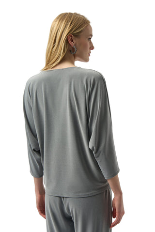 Woman wearing a gray long-sleeve top and pants against a white background